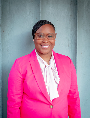 Professional photo of Janae Alexander in a pink suit against a grey background.