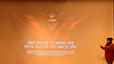 A presentation about Hell House on a projector screen with a presenter talking about the topic.
