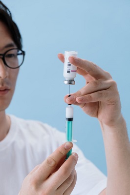 A man taking liquid out of a vial with a syringe.