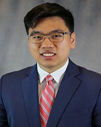 Headshot for Kai Li wearing a blue blazer, white shirt, and red striped tie.