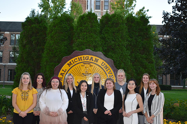 A group of IPR students pose in front of the Central Michigan University seal in Warriner hall.