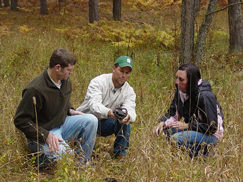 USDA member along with two BIO 541 students kneeling in a field reviewing results from sampling equipment.