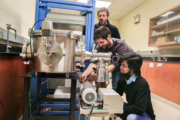 Three physics graduate students setting up laser equipment.