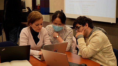 Three students examining data on a laptop