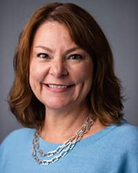 Cheryl Danner, Counselor, professional headshot picture,  wearing a light blue shirt, silver necklace with a grey background