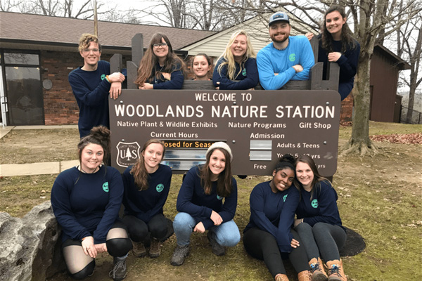 Alternative Break group poses in front of Woodlands Nature Station sign