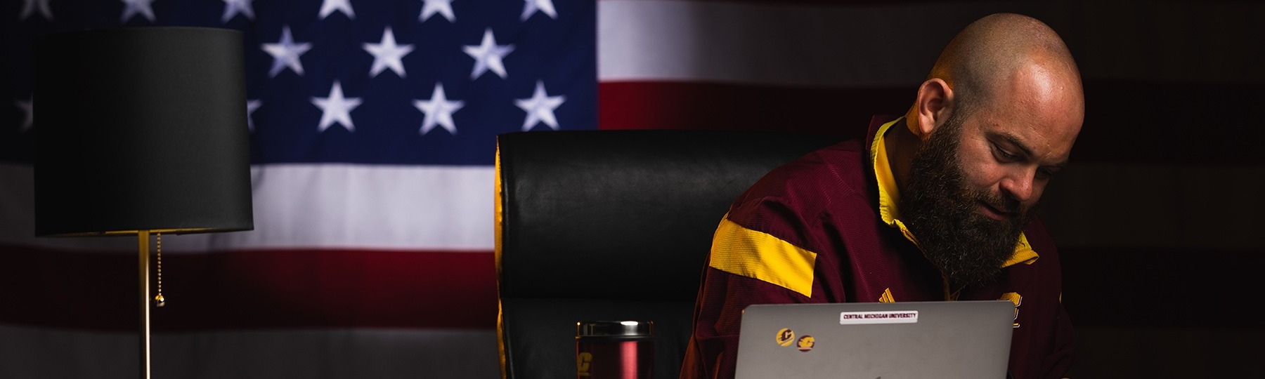 Veteran studying at a desk with the United States flag in the background.
