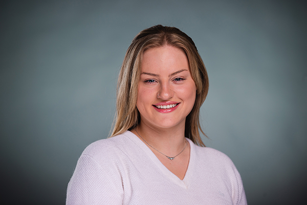 Professional headshot of a smiling Lauren Allen wearing a white shirt against a light grey background.