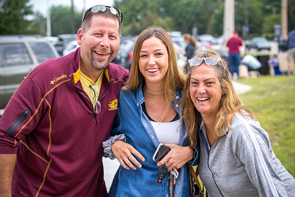 Dad, daughter and mom pose for camera during move-in day