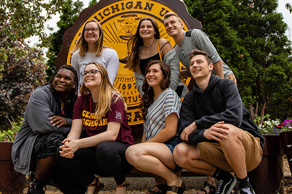 Several CMU students posing for a photo in front of the university seal.