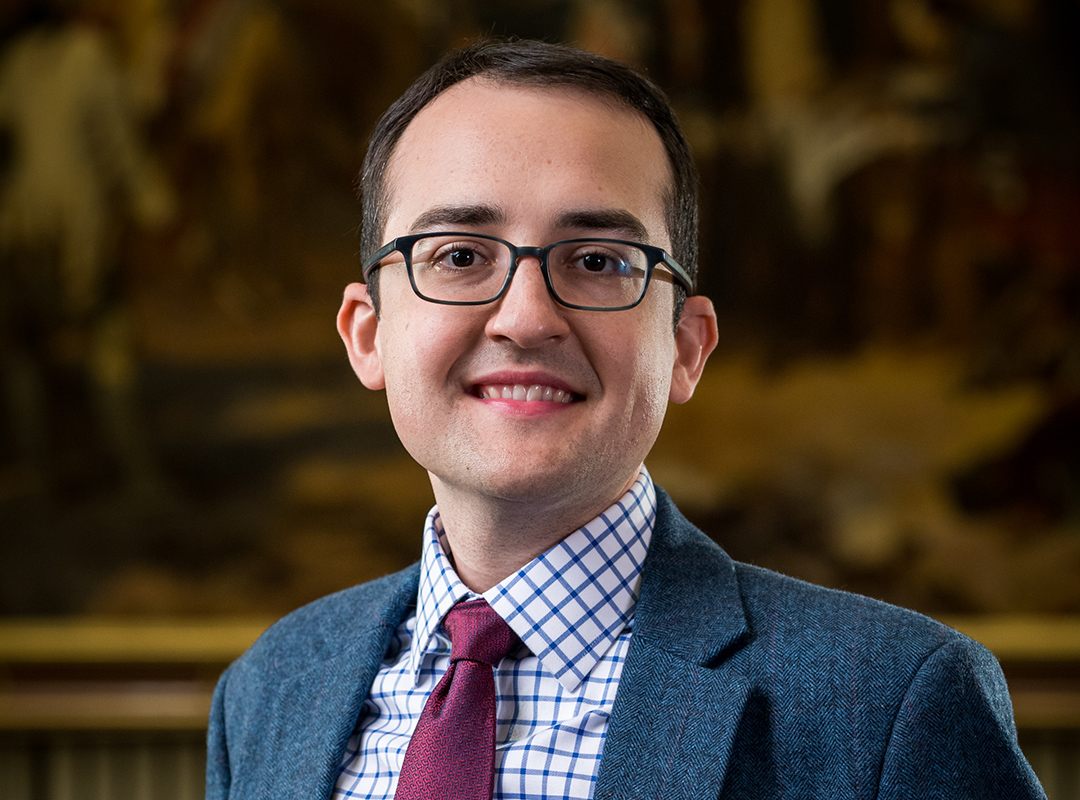 Matthew Skic wears glasses, a collared shirt, tie and blazer in a professional headshot.