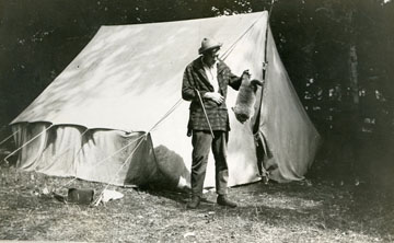 Ernest Standing in front of the tent he slept in at Windemere with a racoon.  Image courtesy of Jim Sanford and Clarke Historical Library