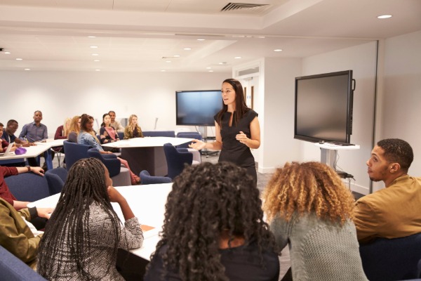 a librarian standing in front of a classroom of students teaching them about how to use the library.