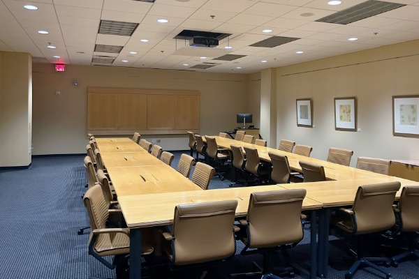 Strosacker Room featuring a large room with tables arranged in a large U shape with tan computer chairs surrounding the tables.
