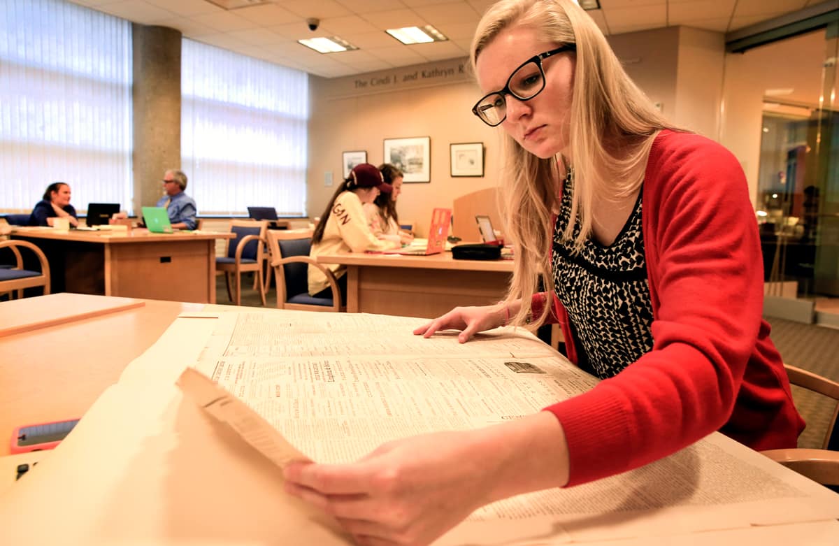 Student looking at a historical newspaper in the Clarke Reading Room.