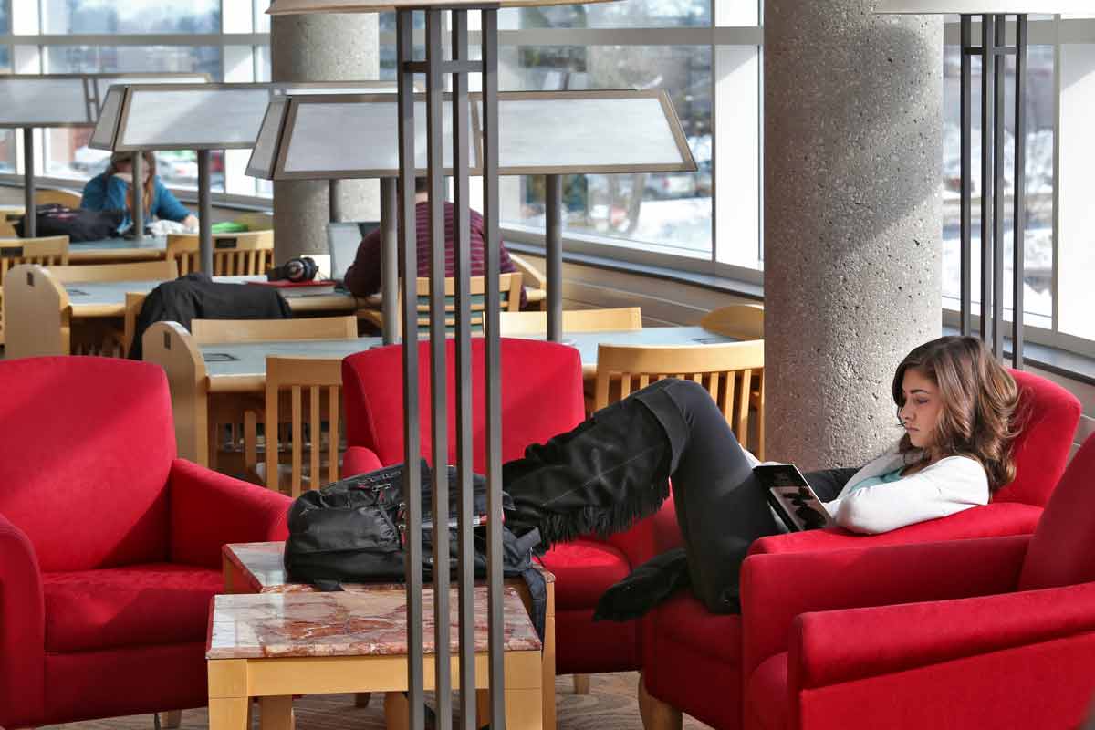 Person sitting in a comfortable chair and reading in the general study sections of the Library.