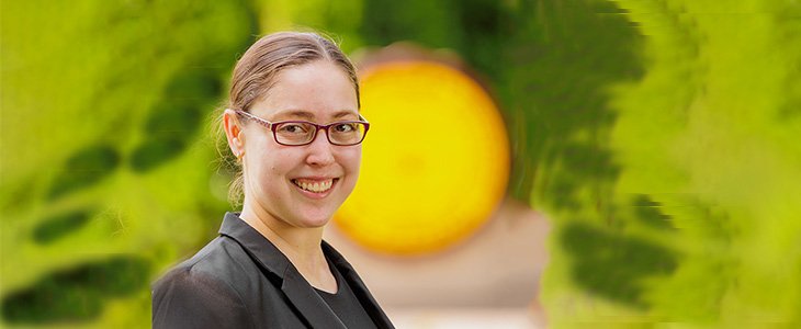 Professional headshot of Elizabeth Heitsch in black blazer against blurred CMU Seal outside