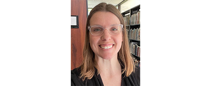 Andrea Howard smiling for a headshot, wearing a black shirt and glasses.