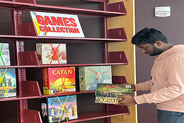 Male student looking at board game from the board game collection at Central Michigan University Libraries - Park Library.