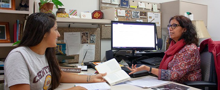 A librarian in front of a computer gives a consultation to student who sits across a desk