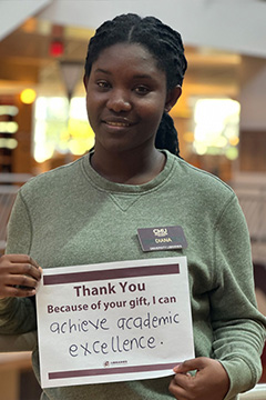 Library Scholarship Recipient Diane Gyimah holding a sign that reads 