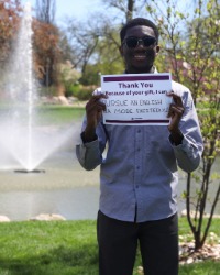 a smiling man holding a sign that says, 