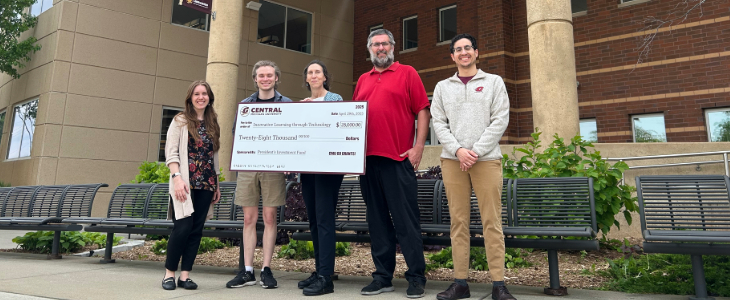 5 Library employees stand holding a Go Grant big check in front of the Park Library.