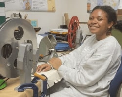 Clarke Historical Library Student Employee Kendall wearing a white long sleeve shirt with a microfilm machine