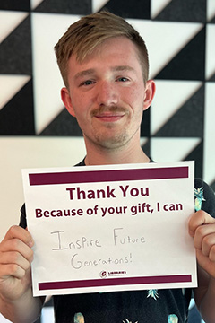 Library Scholarship Recipient Larry Laponsie holding a sign that reads 