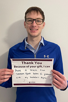 Library Scholarship Recipient Lucas Warnke holding a sign that reads 