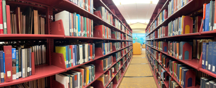 Image of the 2nd floor book stacks, viewing the stacks from one end looking down to the other end with books on both sides.