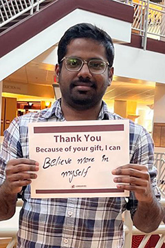 Library Scholarship Recipient Sai Chand Venapally holding a sign that reads 
