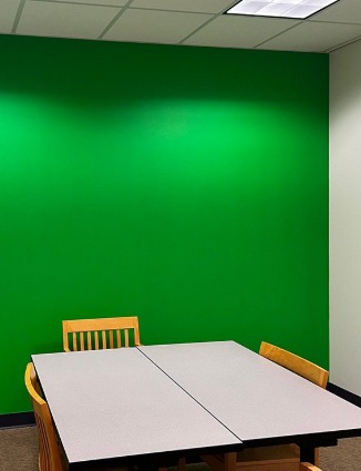 Photo of green wall room with a desk in the center of the room and one wall painted green