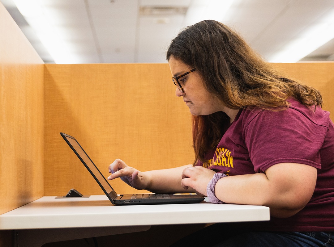 Student sitting in library carrel working on a laptop