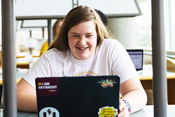 Student working on a laptop at a table in the Library.