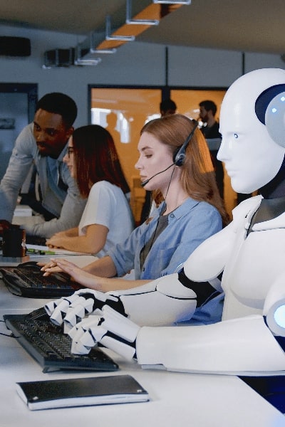 Two individuals typing alongside a robot that is also typing.