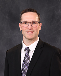Chris Hamlyn portrait, showing head and shoulders, smiling, on a gray background