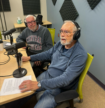 Ralph Baber and Jim Carroll sit in the podcast studio wearing headphones