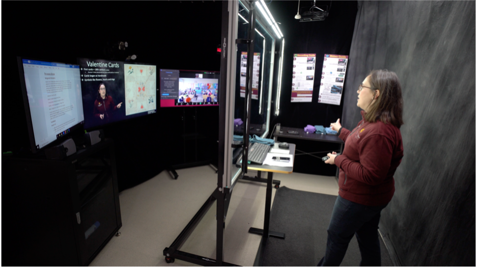 presenter using the lightboard to share course content while also referencing screens behind the board