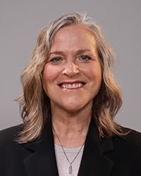 JoDell Heroux wearing a black shirt and smiling while posing for a professional headshot.
