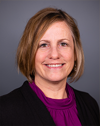 A head and shoulders portrait of Jodi Brookins Fisher on a gray background.