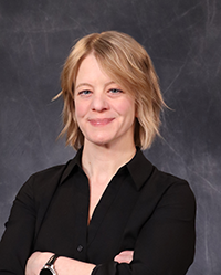 Kelly Murphy portrait, showing head and shoulders, smiling, on a gray background