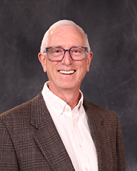 Larry Lemke portrait showing head and shoulders, smiling, on a gray background