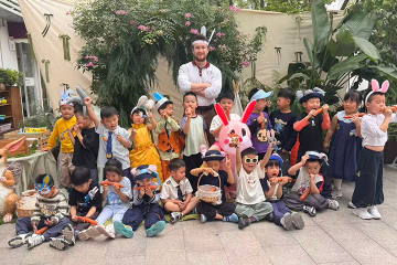 Adult male standing with his young students who are wearing bunny ears and holding carrots