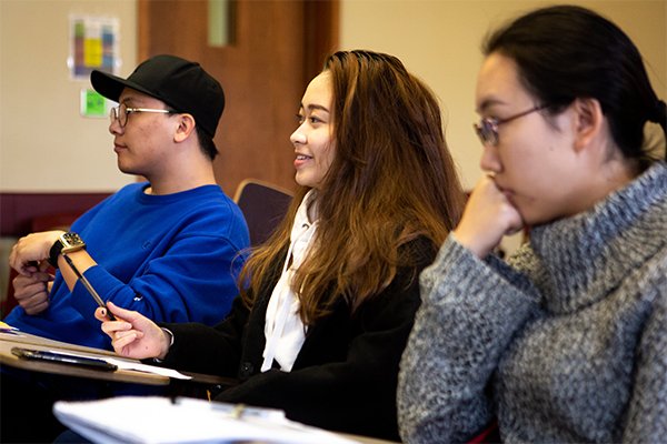 Three international students sitting in a classroom.