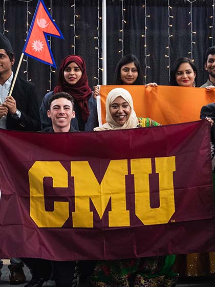 International students holding a CMU flag at the International Student Expo.