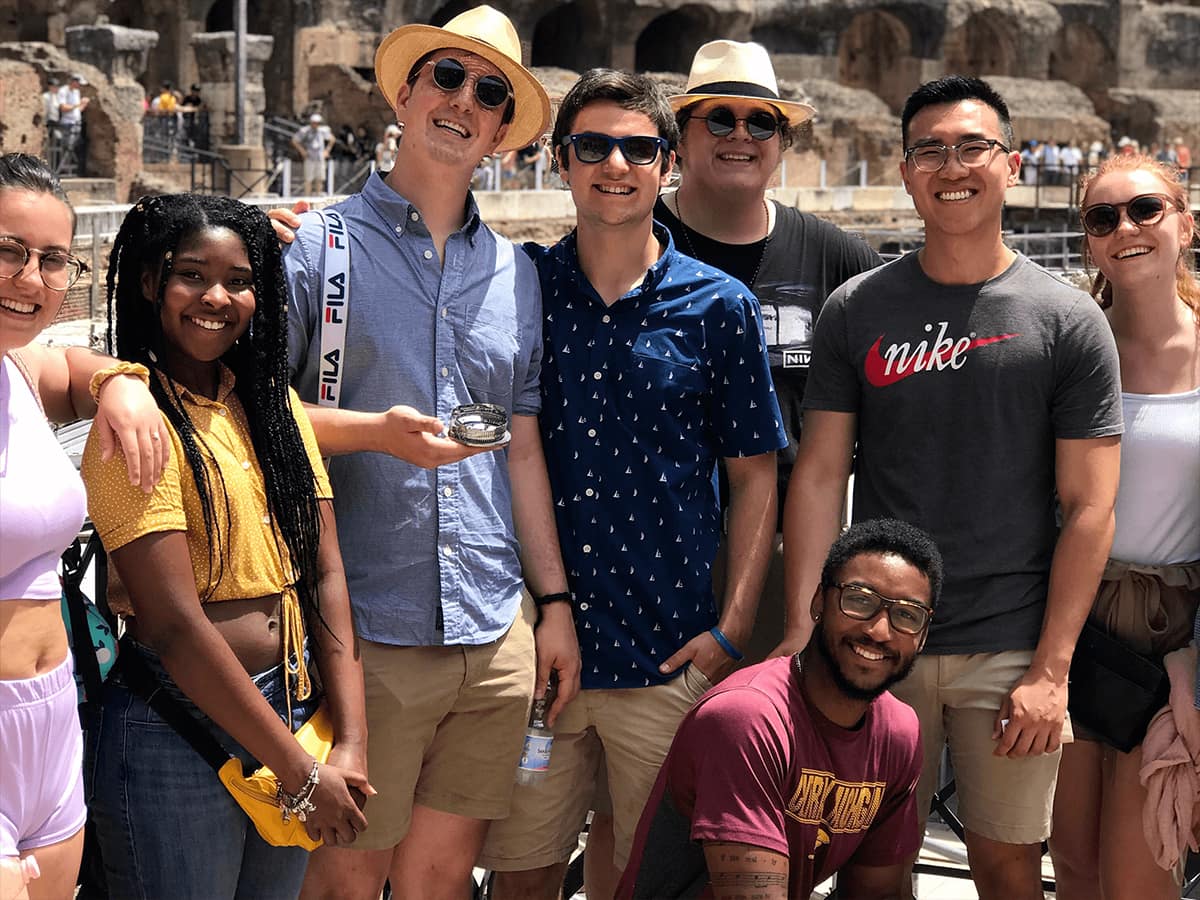 Group of eight people standing in front of a structure.