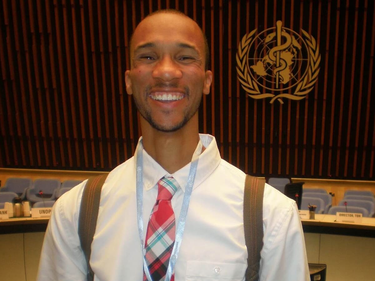 A male student smiles for the camera at a conference.