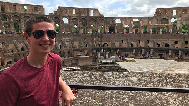 A Central Michigan University student standing in front of a Roman amphitheater.
