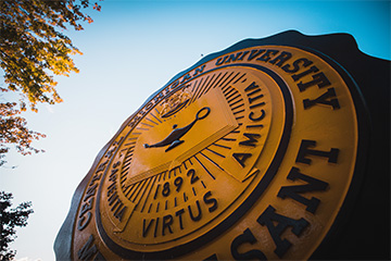 The Central Michigan University seal under a bright blue sky.
